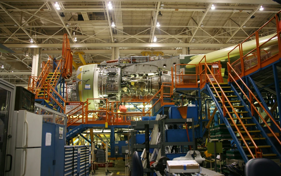Atelier industriel aéronautique avec techniciens travaillant sur moteur d'avion monté sur structure d'assemblage