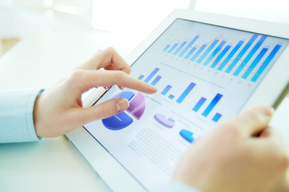 Un professionnel en environnement industriel ou de bureau examinant attentivement un document imprimé, un rapport ou un plan détaillé relatif à la sécurité ou la prévention des risques (visible par son contenu : schémas de danger, matrices d'évaluation des risques, procédures SST), en train de l'expliquer ou de le valider auprès d'une équipe ou d'un client. L'image doit montrer des livrables tangibles et professionnels intégrés concrètement dans un processus opérationnel d'une organisation.